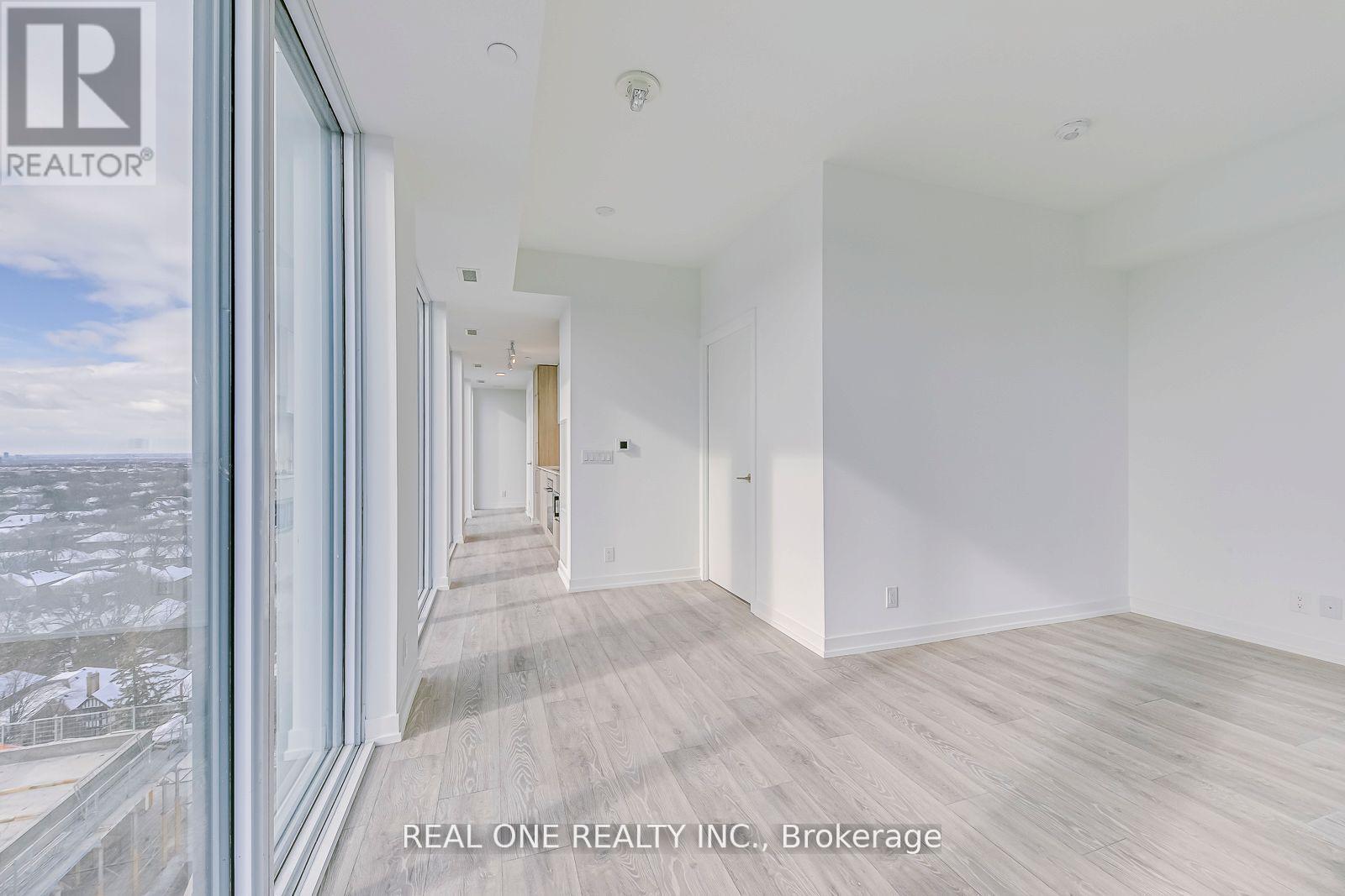 A spacious room with wooden flooring and white walls, part of a real estate listing.