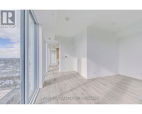A spacious room with wooden flooring and white walls, part of a real estate listing.