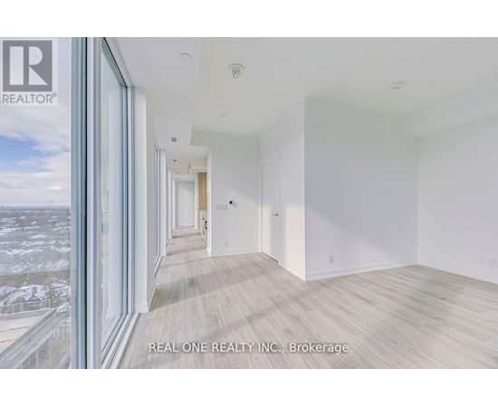 A spacious room with wooden flooring and white walls, part of a real estate listing.