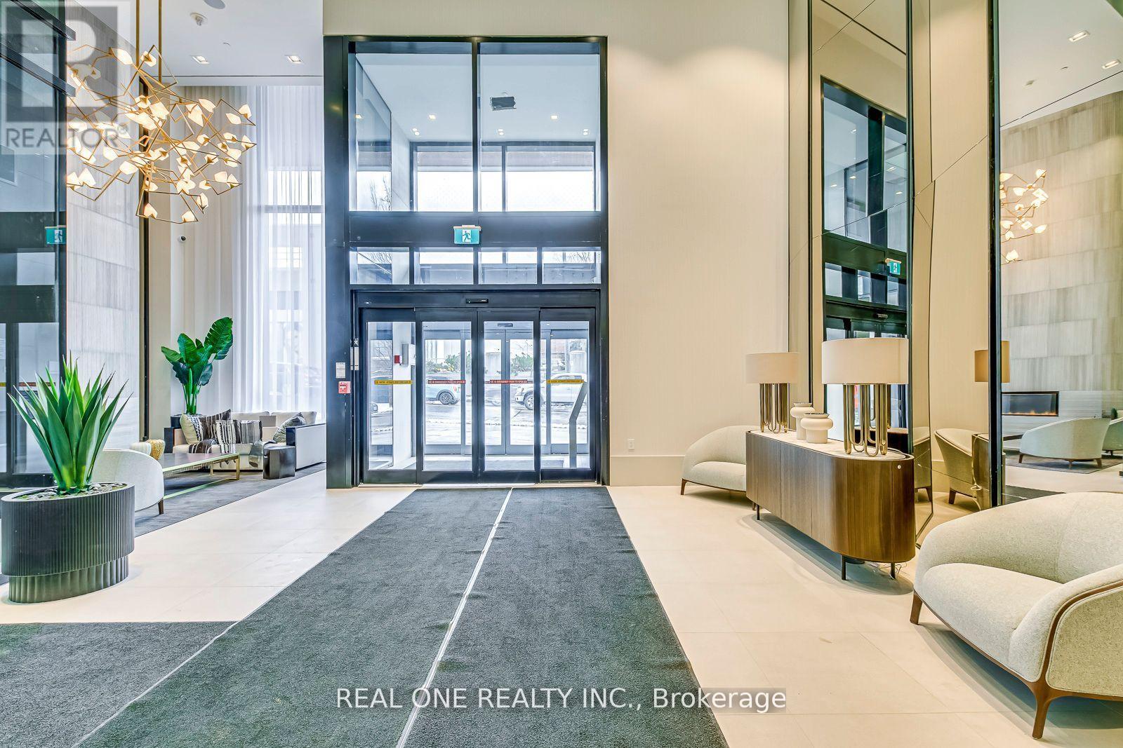 A reception area with a large glass door and a plant in a pot.