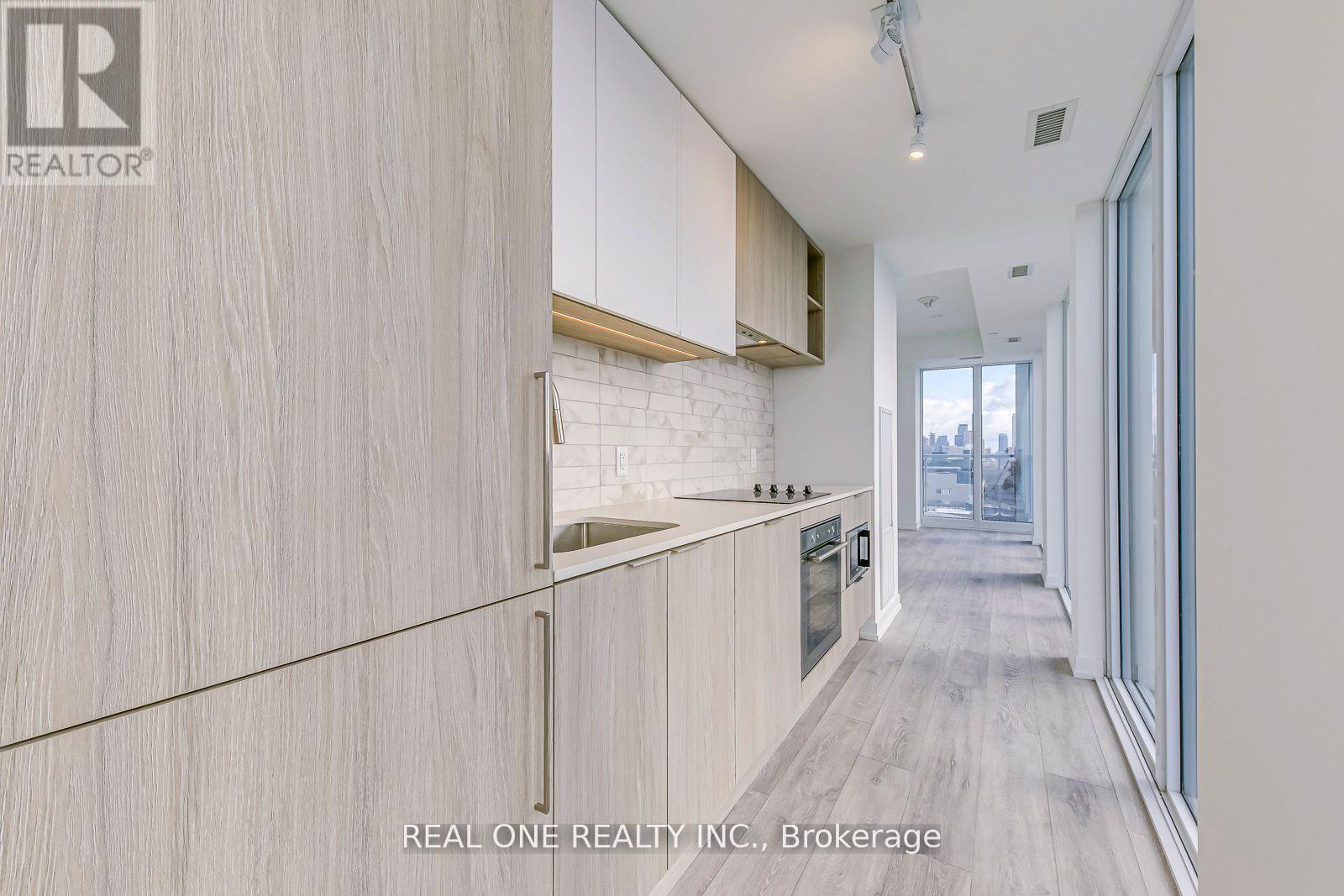 A modern kitchen with wooden cabinets and a white brick accent wall.