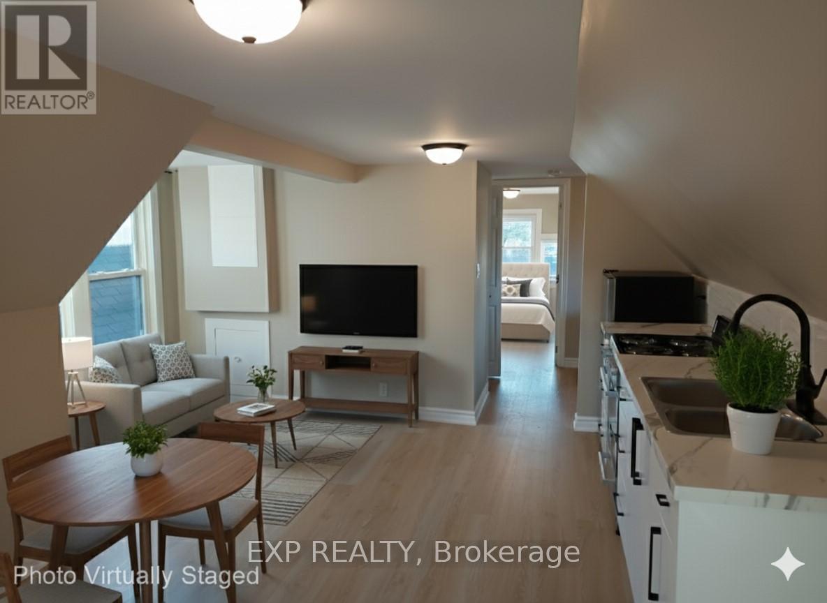 A living room with a television and a kitchen area in the background.