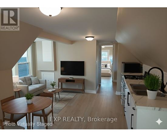 A living room with a television and a kitchen area in the background.