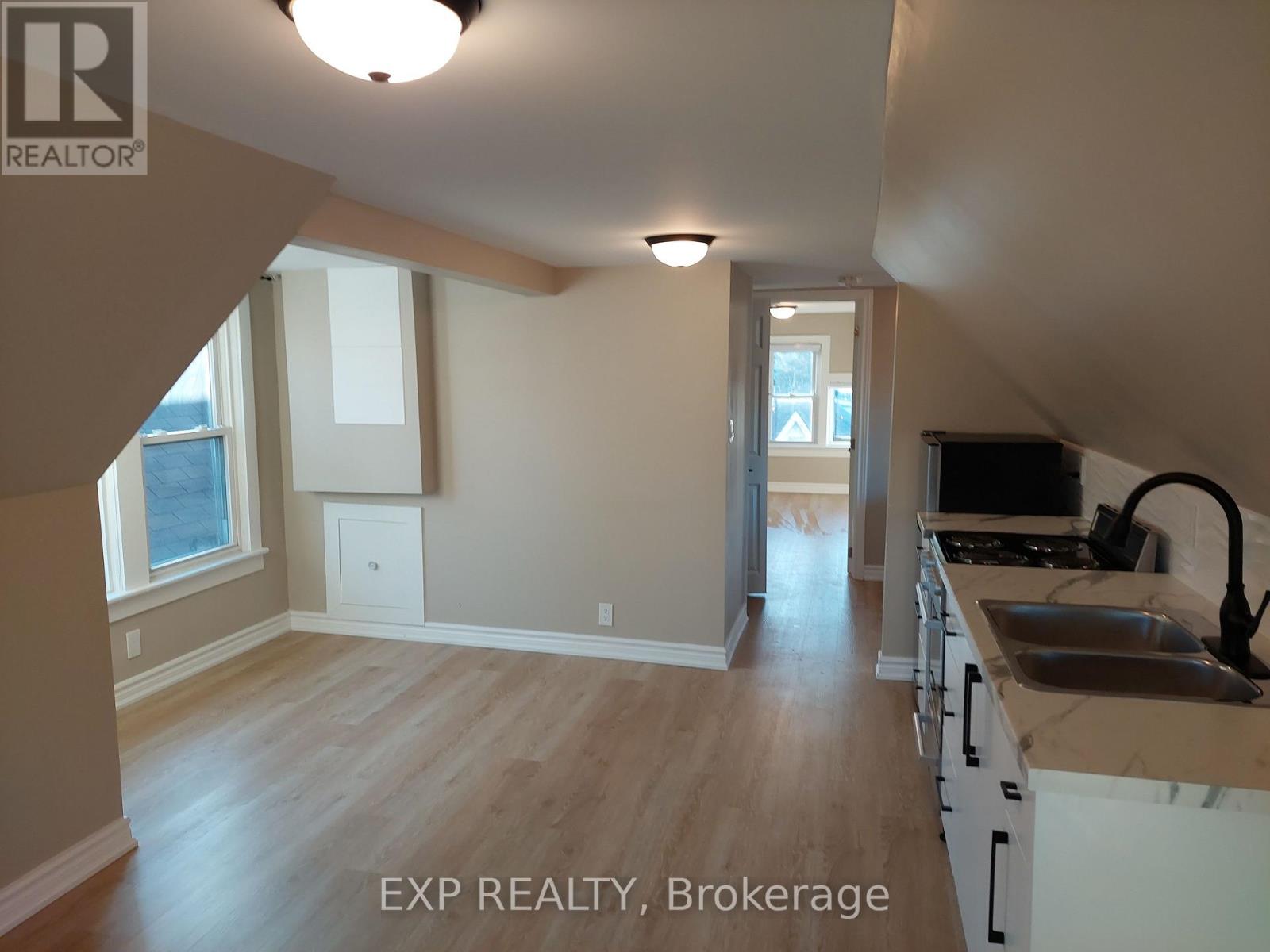 A kitchen with white cabinets and a wooden floor.