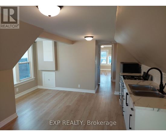 A kitchen with white cabinets and a wooden floor.