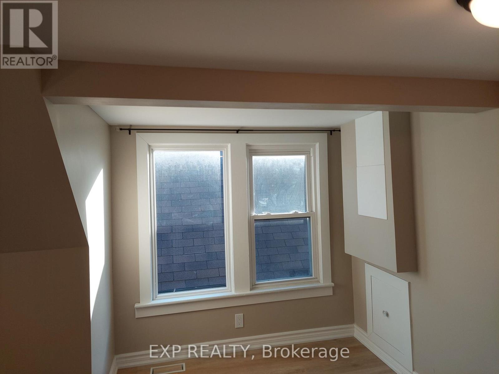 A room with a window and a sign that says EXP REALTY, Brokerage.
