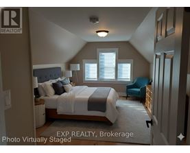 A bedroom with a bed, chair, and window.