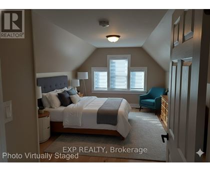 A bedroom with a bed, chair, and window.