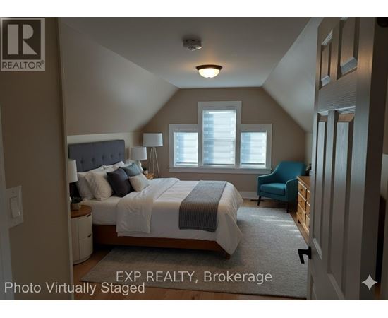A bedroom with a bed, chair, and window.