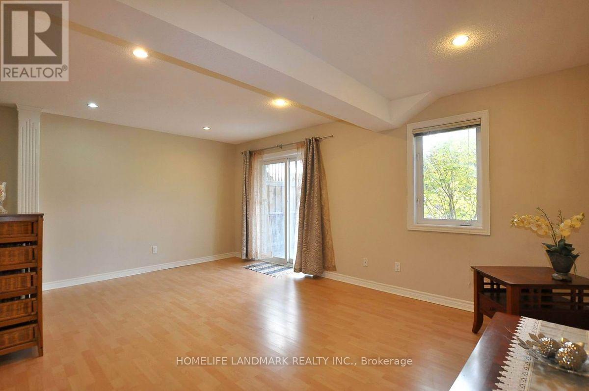 A spacious room with wooden floors and a large window with curtains.