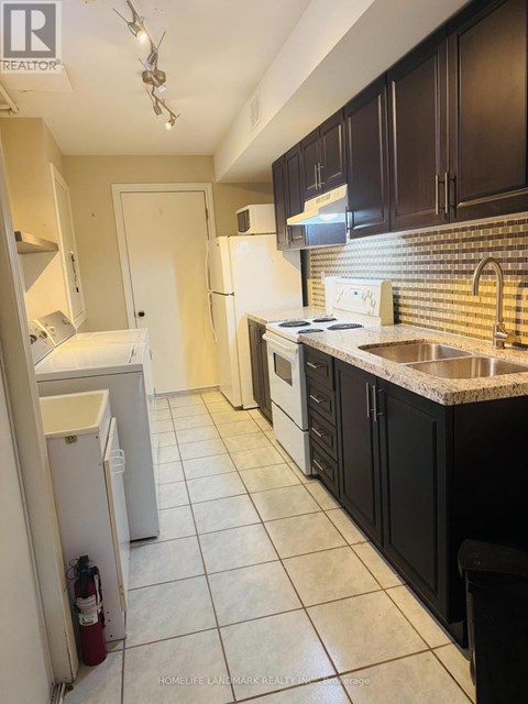 A kitchen with black cabinets and a white fridge.