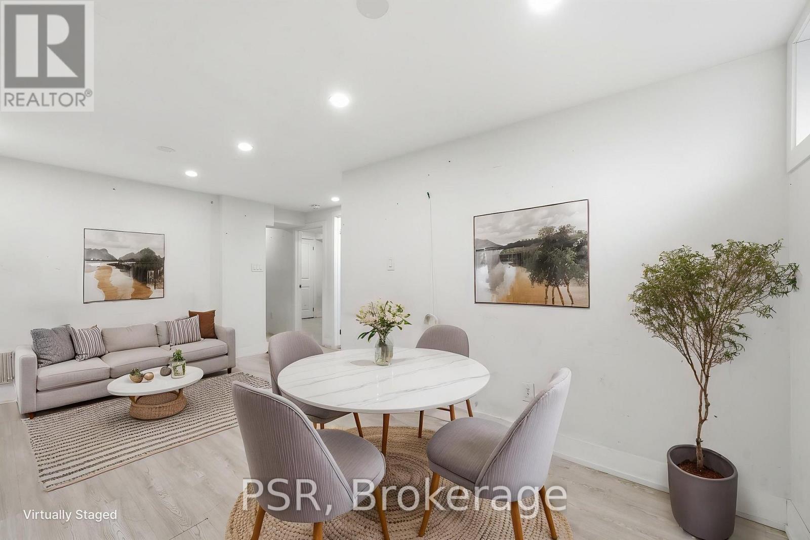 A modern living room with a dining table set up with chairs and a potted plant.