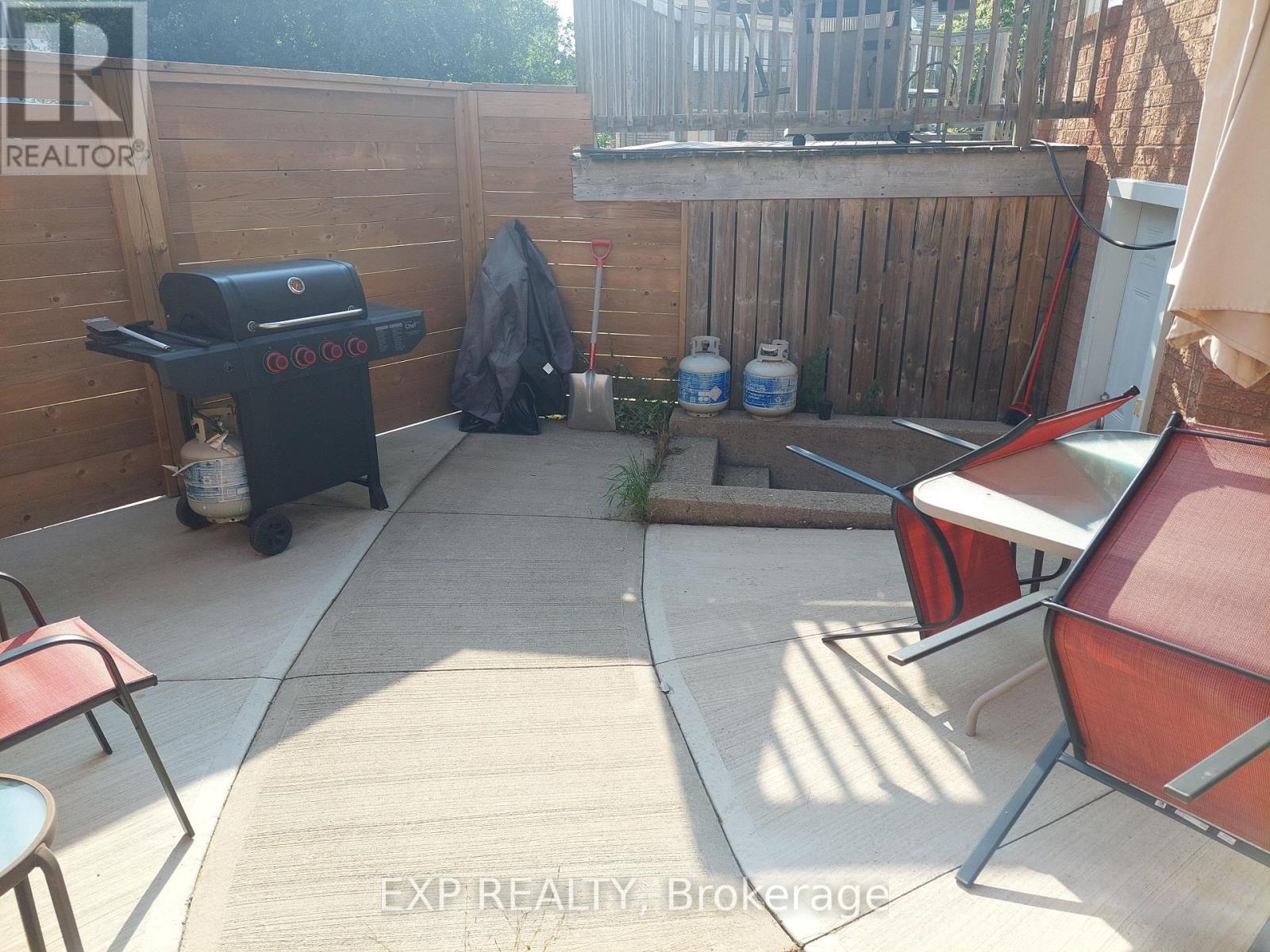 A backyard with a BBQ grill, chairs, and a table.