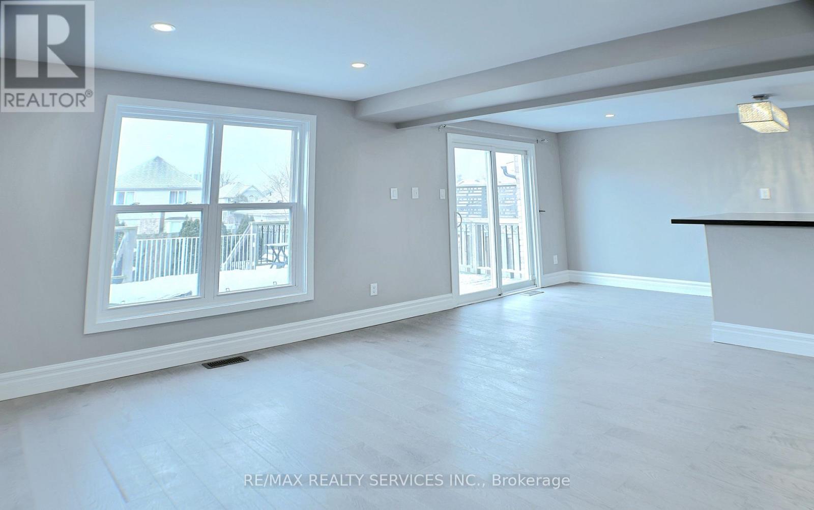 A spacious room with a large window and a door leading to a balcony.