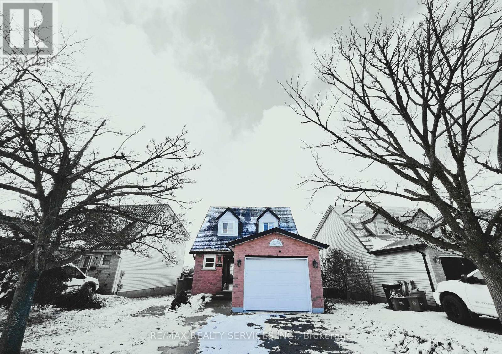 A red house with a white garage door in the middle of a snowy street.