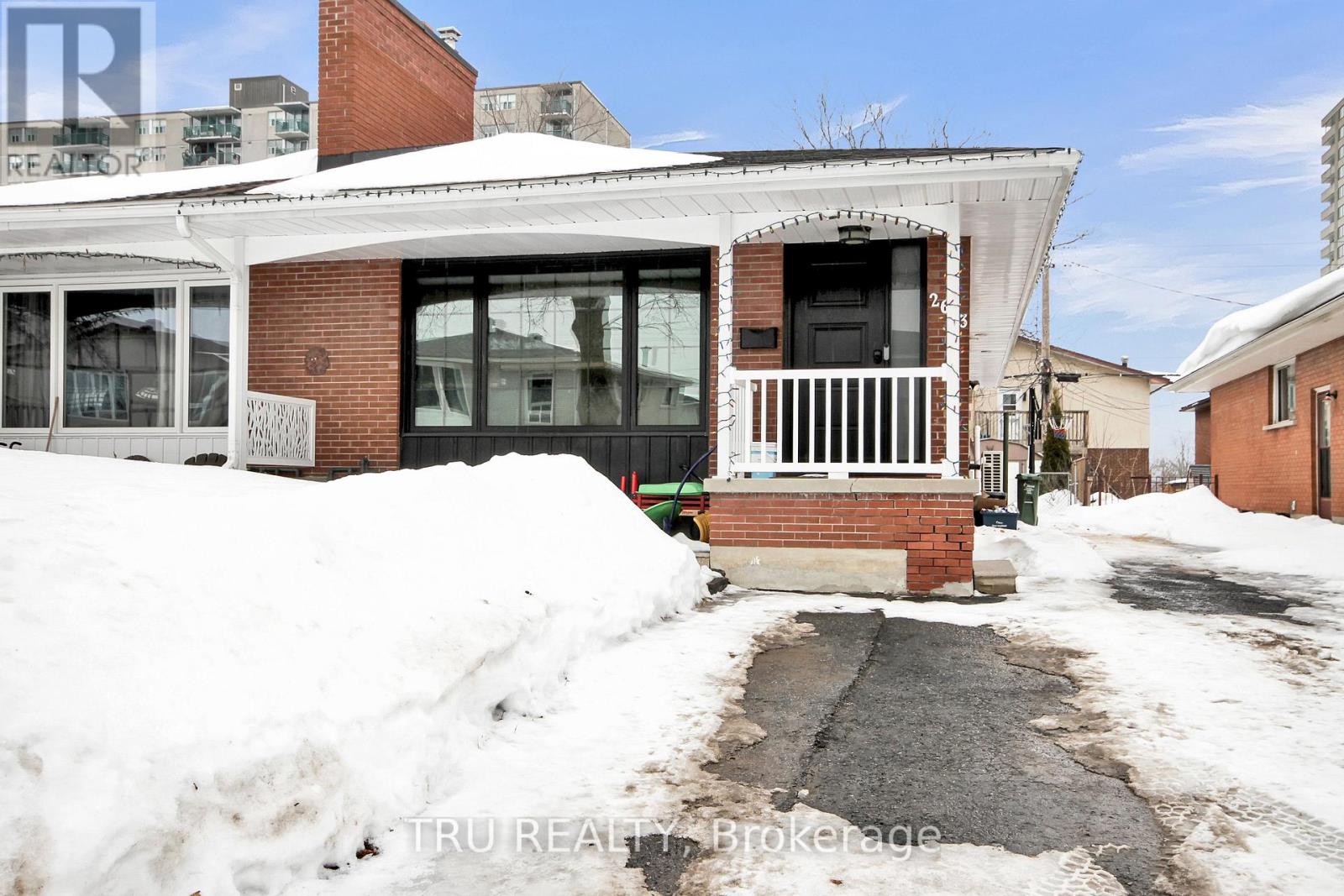 A house with a white roof and a brick chimney is surrounded by snow.