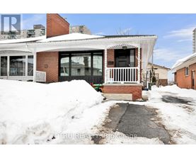 A house with a white roof and a brick chimney is surrounded by snow.