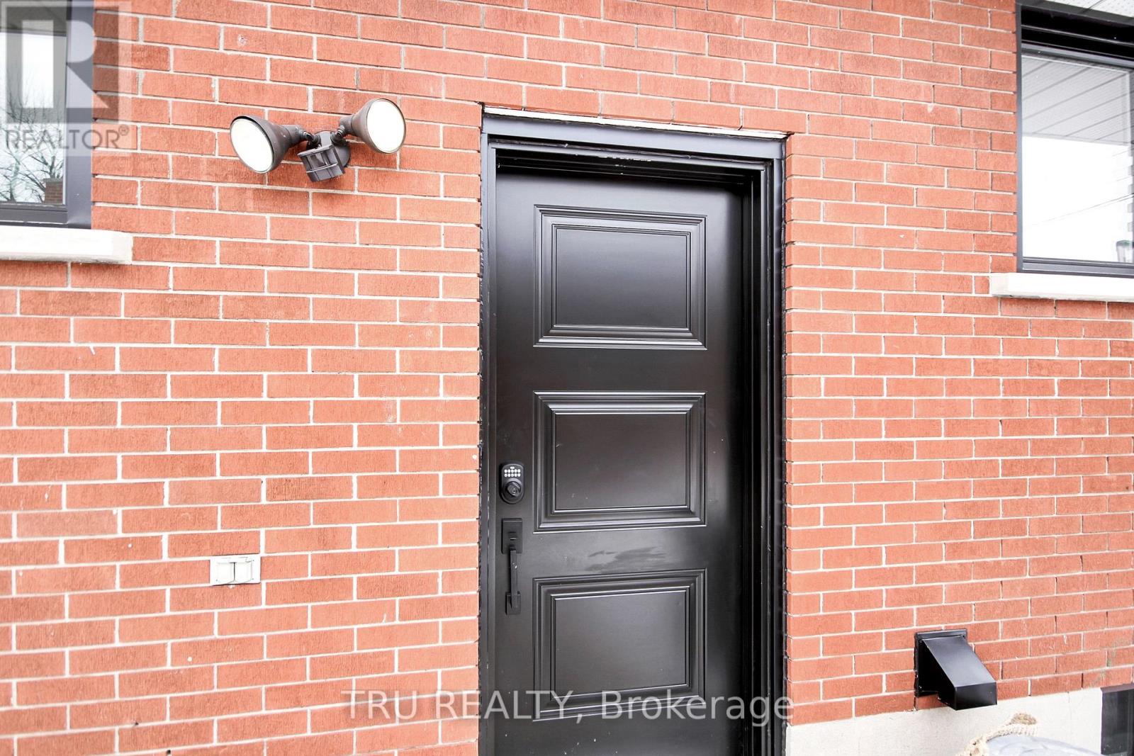 A black door is on a red brick wall.