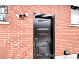 A black door is on a red brick wall.