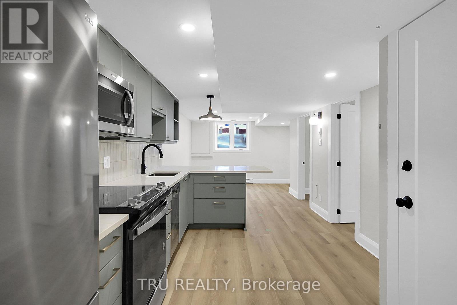 A modern kitchen with stainless steel appliances and wooden flooring.