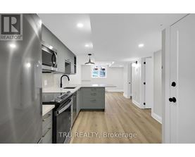 A modern kitchen with stainless steel appliances and wooden flooring.