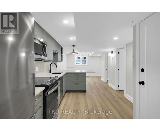A modern kitchen with stainless steel appliances and wooden flooring.