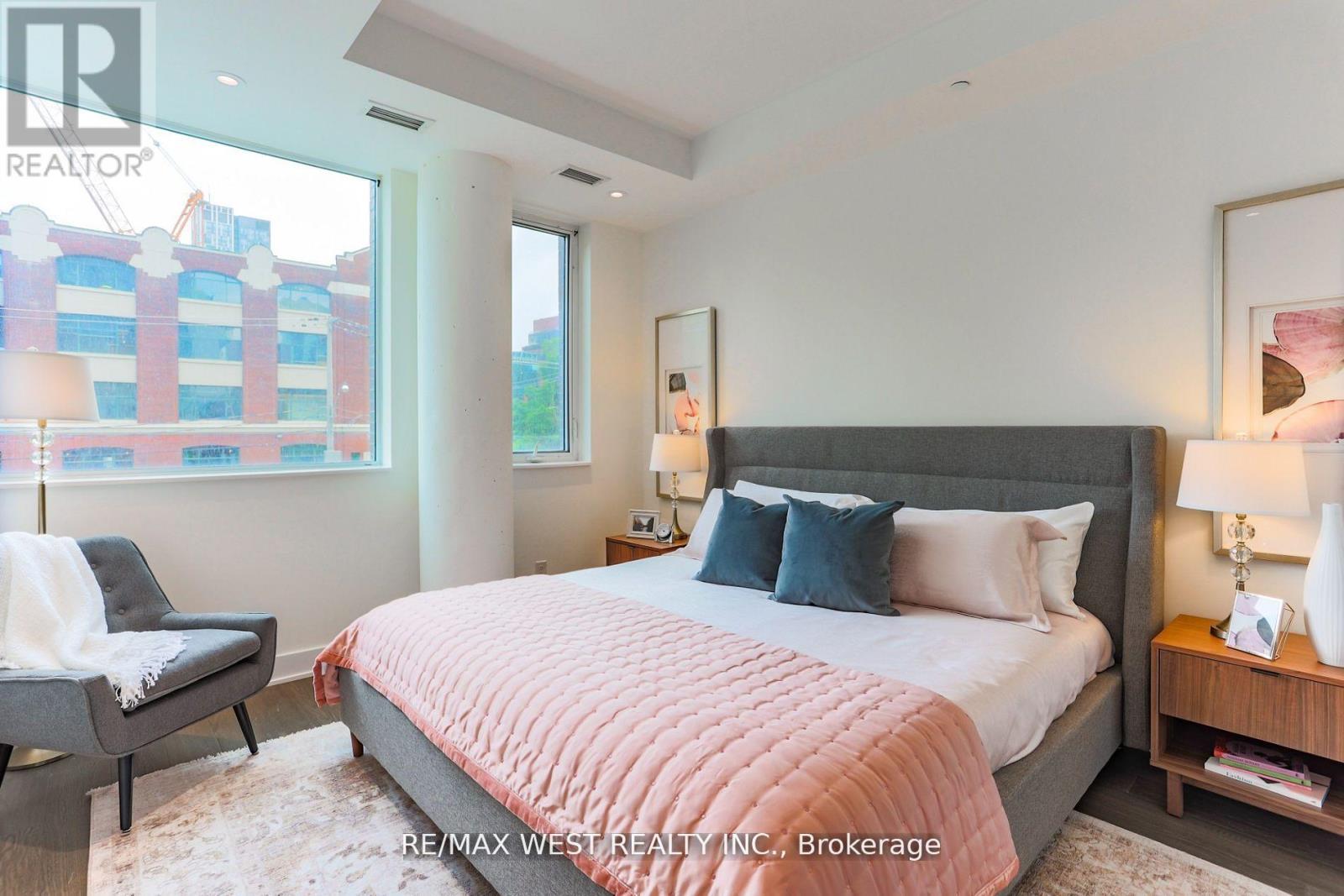 A bedroom with a large bed and a chair.