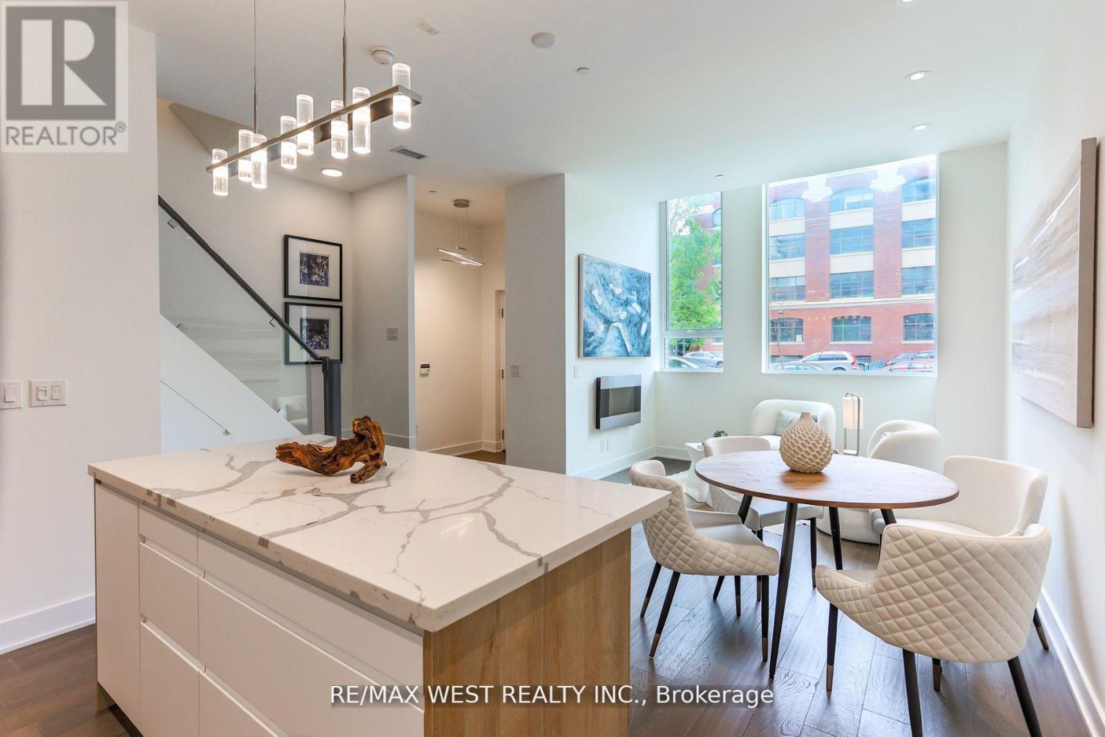 A modern kitchen with a marble island and white chairs.