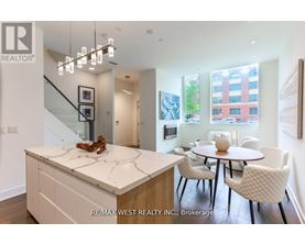 A modern kitchen with a marble island and white chairs.