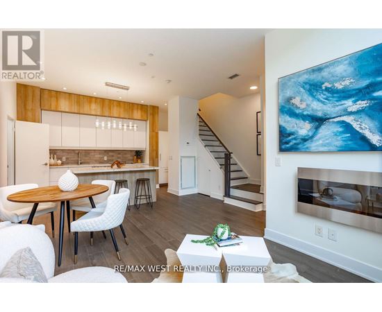 A modern living room with a wooden dining table and white chairs.