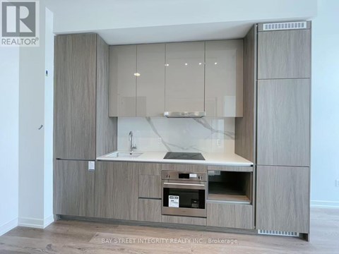 A modern kitchen with a sink, stove, and cabinets.