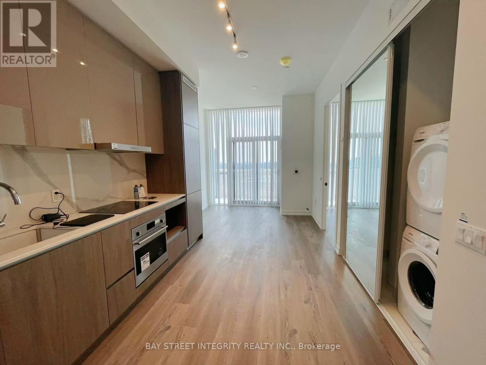 A modern kitchen with wooden floors and a washing machine in the corner.