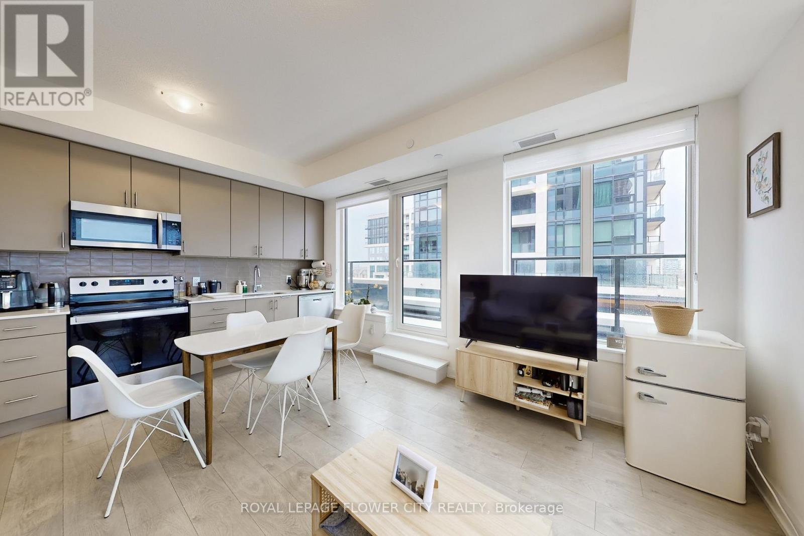 A modern kitchen with white chairs and a wooden table.