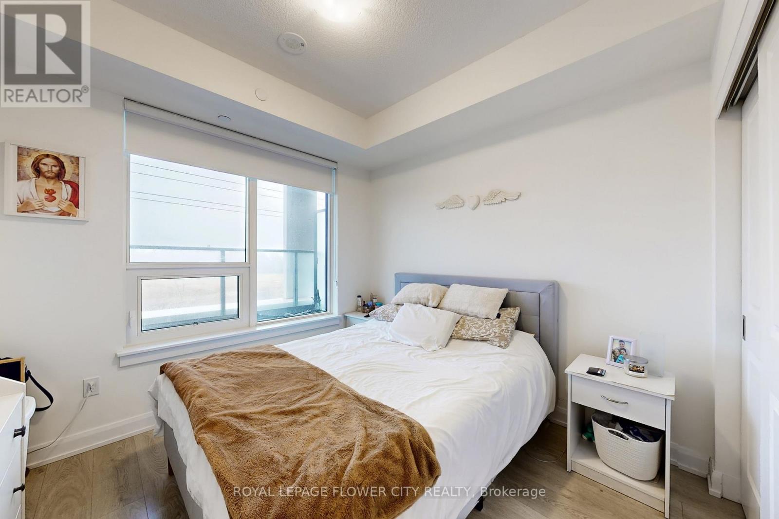 A bedroom with a bed, nightstand, and window.