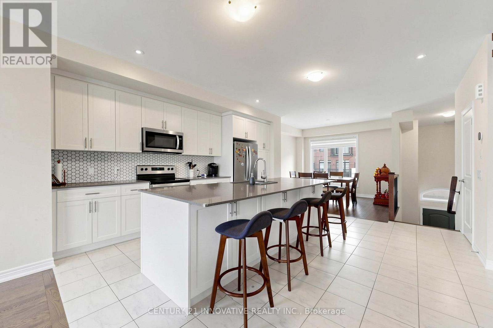 A kitchen with white cabinets and a large island with bar stools.