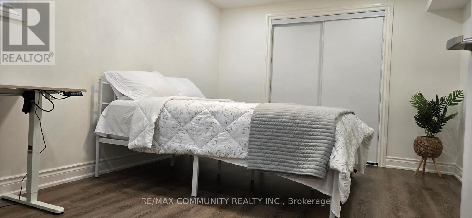A bedroom with a bed covered in a white comforter.