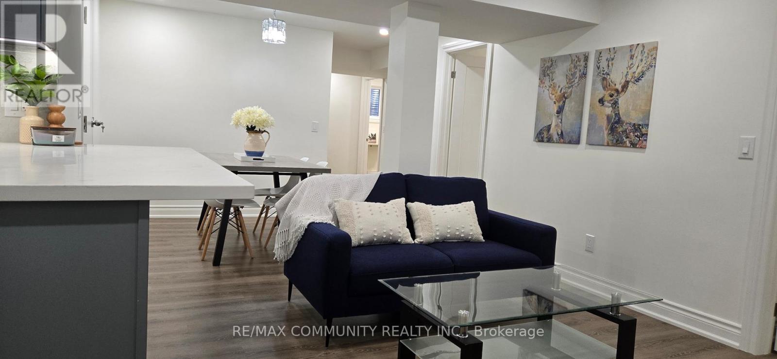 A blue couch with white pillows is in the middle of a room with a glass table.