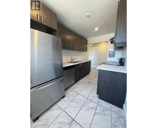 A modern kitchen with a stainless steel refrigerator and dark wood cabinets.