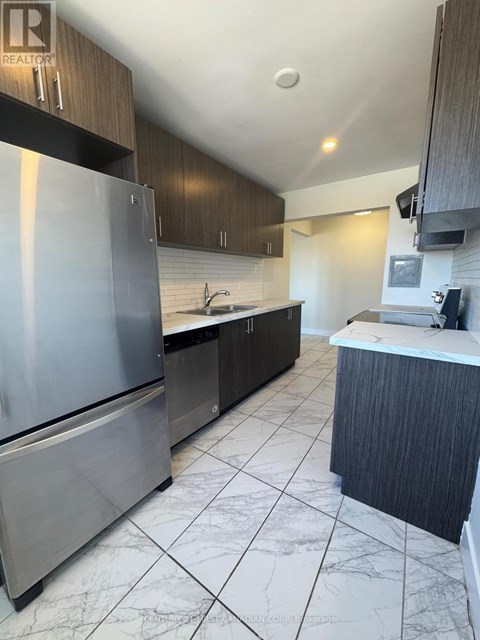 A modern kitchen with a stainless steel refrigerator and dark wood cabinets.