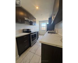 A kitchen with dark wood cabinets and white countertops.