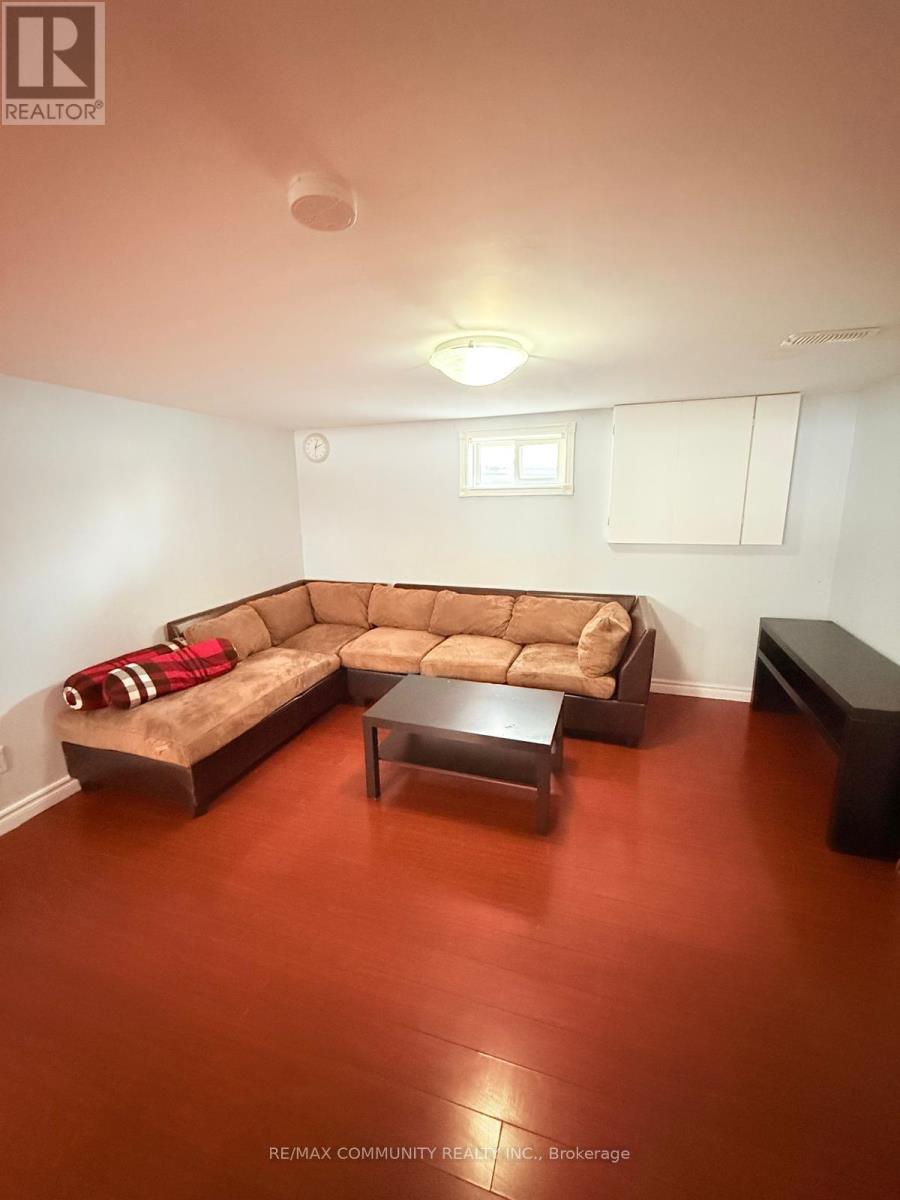 A brown couch with a red throw on it sits in a room with a wooden floor.