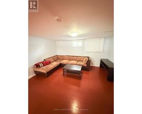 A brown couch with a red throw on it sits in a room with a wooden floor.