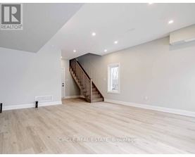 A spacious room with a staircase and a window.
