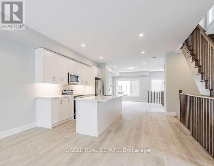 A spacious kitchen with white cabinets and a wooden staircase.