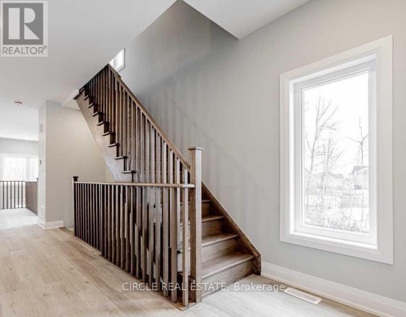 A wooden staircase in a house with a window showing trees outside.