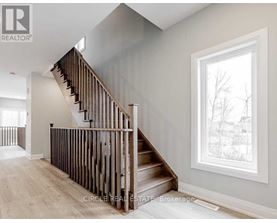 A wooden staircase in a house with a window showing trees outside.