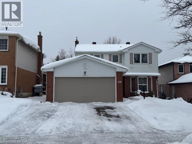 A house with a garage in front of it is covered in snow.