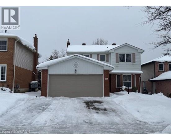 A house with a garage in front of it is covered in snow.
