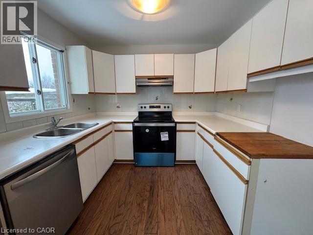 A kitchen with white cabinets and a wooden counter top.