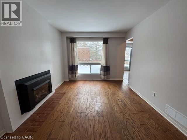 A spacious room with a fireplace and wooden flooring.